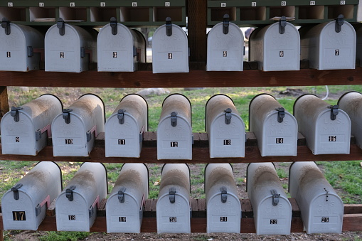 Linee up and numbered white country mail boxes in a rural area.  Lines, stacked and numbered ready to receive mail.
