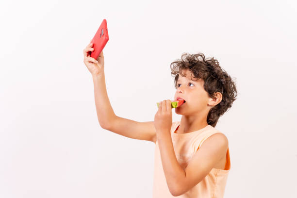 istock Boy eating a watermelon and taking a selfie, summer vacation. White background with copy paste 1401610429