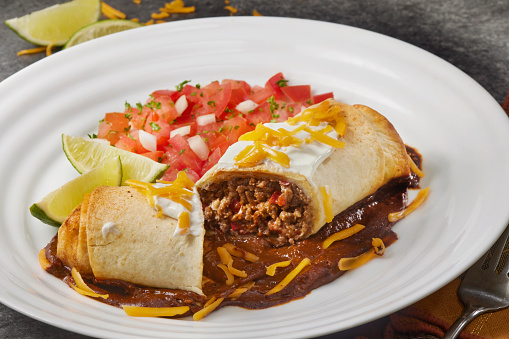 Baked Beef  Burrito with Red Peppers, Onions, Cheddar Cheese Sour Cream, Pico de Gallo and Mole Sauce