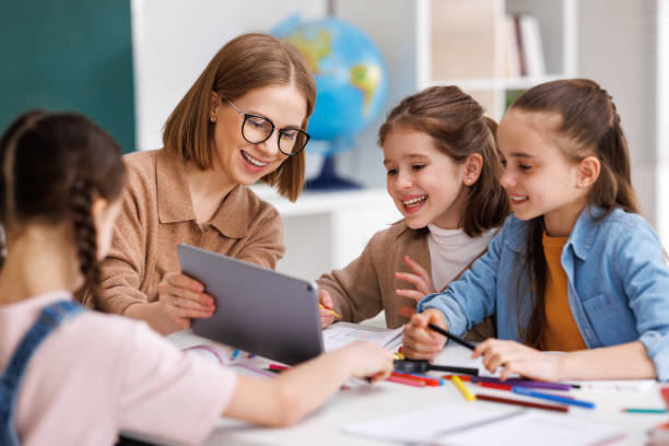 femme avec tablette enseignant aux enfants à l’école - enseignante photos et images de collection