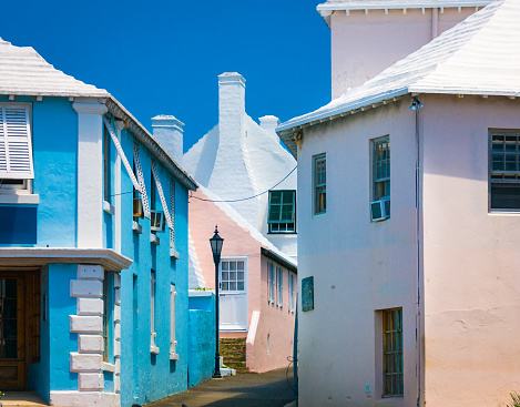 A narrow street in St. George, Bermuda is lined with pastel homes and shops of pink and blue.