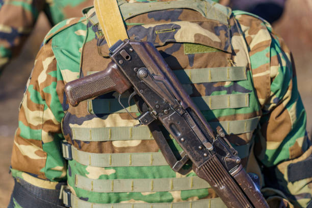 istock Automatic rifle without a magazine on the back of a military man. Background with selective focus and copy space 1401618786