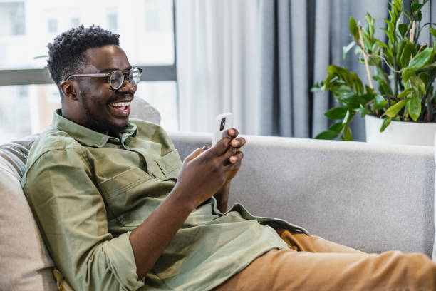 istock Smiling young man is relaxing at home and using mobile phone 1401620931