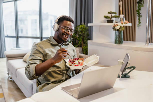 istock African-American young man using laptop at the table while having lunch 1401621088
