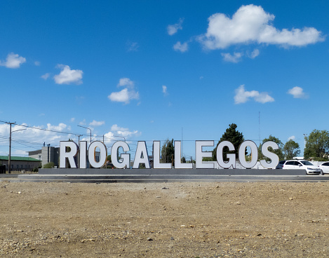 RIO GALLEGOS, ARGENTINA- DECEMBER 22, 2020: welcome sign of the city of Rio Gallegos white and front with blue sky and plenty of space for text
