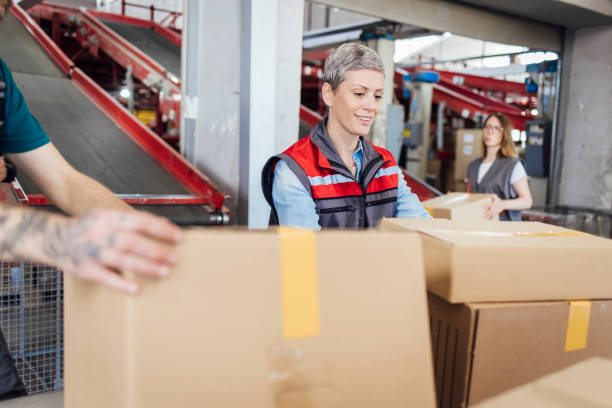 istock Man and woman carrying boxes while working at the warehouse 1401629783