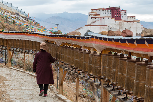 Tibetan pilgrim performing a Kora around Tashilumpo monastery with Little Potala Palace on background
