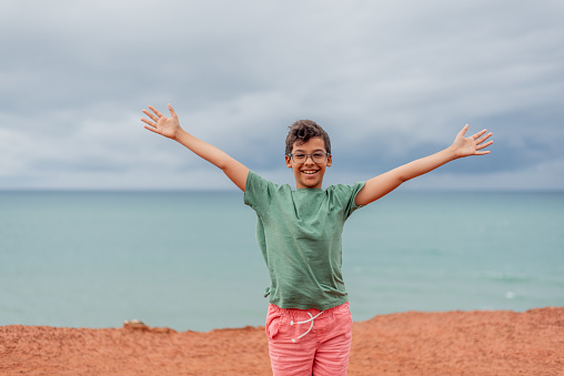 Happy young man with arms raised on the beach