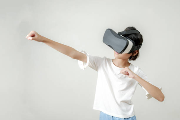Asian child girl with boxing in VR headset training for punch in virtual reality, playing VR game Metaverse digital world technology AR augmented reality control stock photo