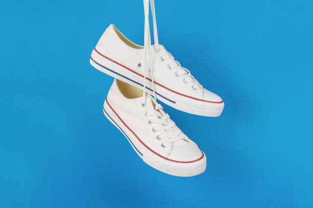 istock White sneakers hanging on laces on a light blue background. 1401646028