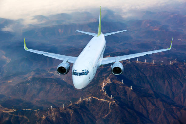 istock White passenger plane flies above the  mountain landscape. Front view. 1401646131