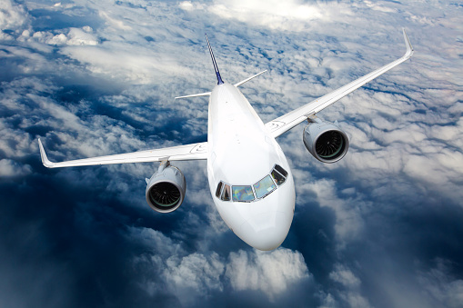 Passenger plane in flight. Aircraft fly high in the sky above the clouds. Front view. Left heeling.