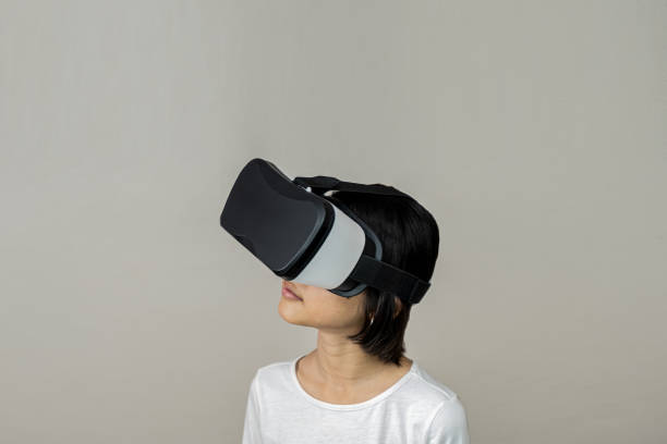 VR application test Asian child girl with virtual reality glasses headset touching air during the VR experience, asia children and learning with virtual reality simulator application test stock photo