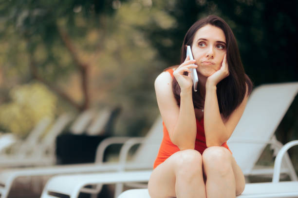 Concerned Stressed Woman Speaking on the Phone by the pool Stressed person unable to relax during summer vacation waiting telephone on the phone frustration stock pictures, royalty-free photos & images