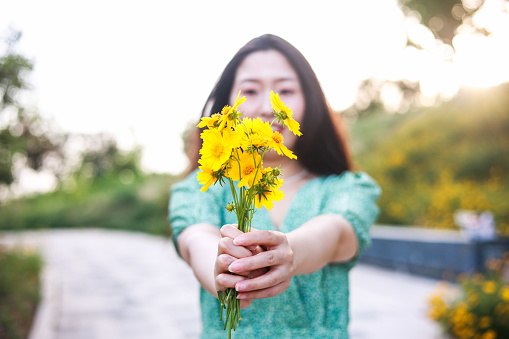 Women hand holding yellow flowers outdoor
