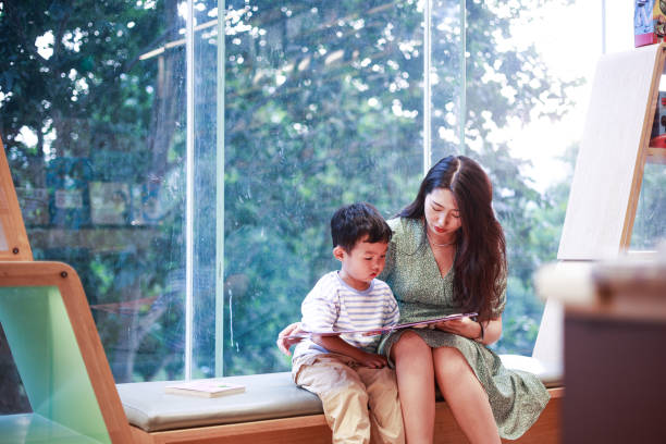 istock Mother and son reading together sitting by window 1401650931