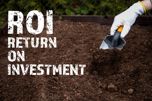 ROI Return on investment. Diging the soil with a garden shovel.