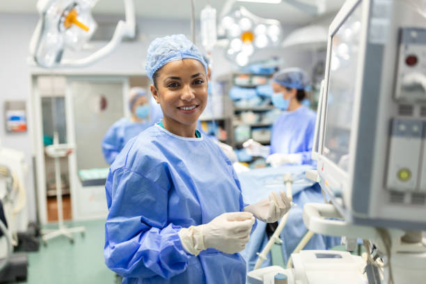 anestesista che controlla i monitor durante la sedazione del paziente prima della procedura chirurgica in sala operatoria dell'ospedale. giovane paziente afroamericana adulta è addormentata sul tavolo operatorio durante l'intervento chirurgico. - nurse doctor healthcare and medicine african descent foto e immagini stock