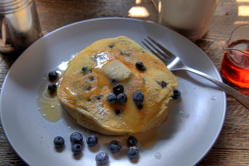 Side view of blueberry pancakes on natural wood surface