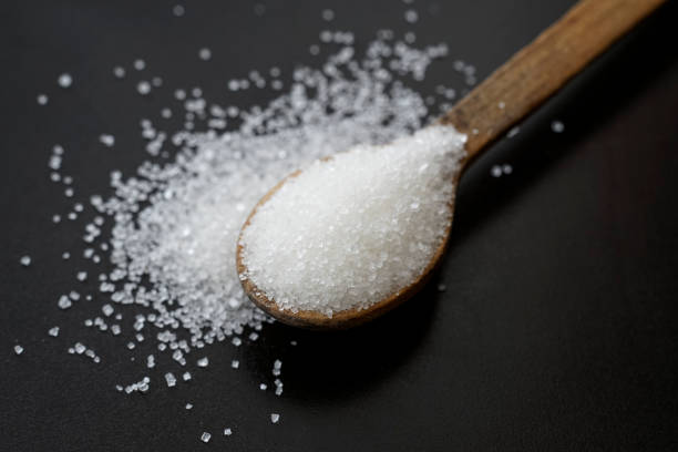 istock sugar crystals on a wooden tea spoon isolated on black 1401661118