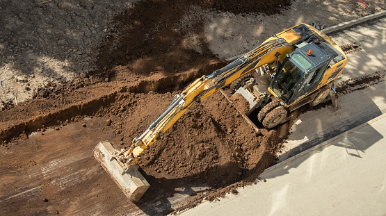 yellow excavator digging a hole at a construction site top view