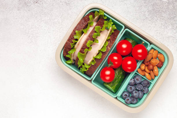 istock School lunch box. Ham and cheese sandwich, vegetables, nuts and berries in a plastic container. Top view. Back to school concept. 1401664143