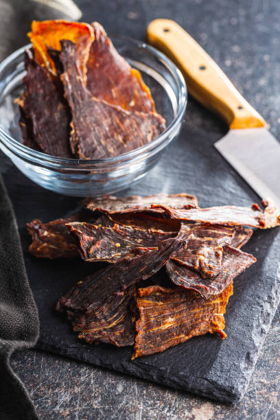 istock Beef jerky meat. Dried sliced meat on cuting board. 1401669116