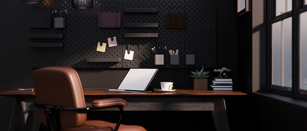 Modern stylish dark home office workplace interior with tablet mockup, accessories and decor on wooden table, black pegboard on black wall, brown leather office chair. 3d rendering, 3d illustration