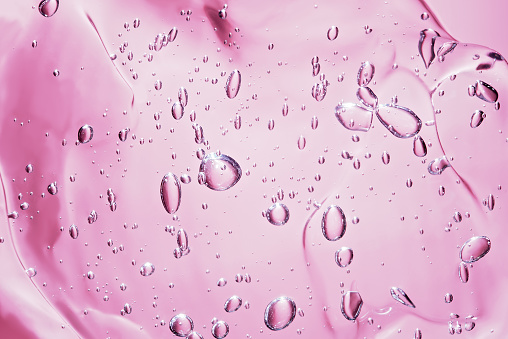 Close up macro Aloe vera gel cosmetic texture pink background with bubbles. Lemongrass gel skincare product. antibacterial liquid with aloe vera, moisturizing. Serum texture. Hand sanitizer