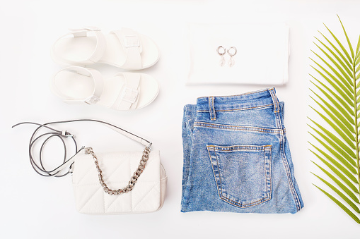 Modern female clothing, sandals and bag on a white background top view.