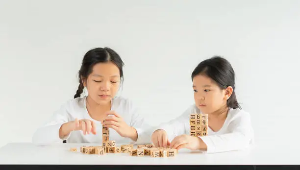 cute little children serious play alphabet block on table, look at letter block of friend. asian children study and learn alphabet, scrabble, crossword in education classroom at small school