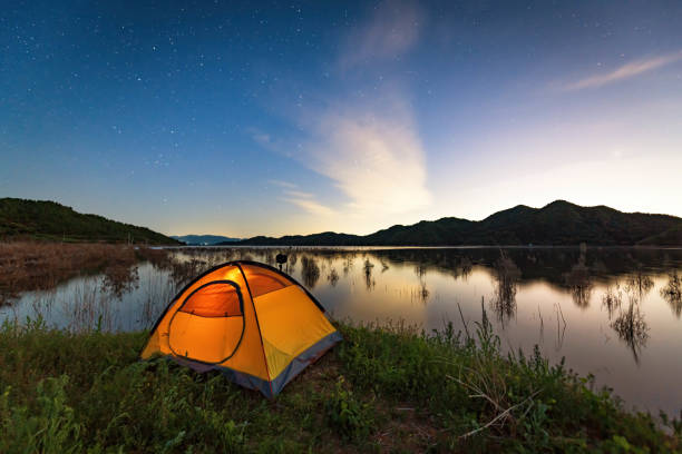 tienda de campaña junto al lago bajo el cielo estrellado - waterland fotografías e imágenes de stock