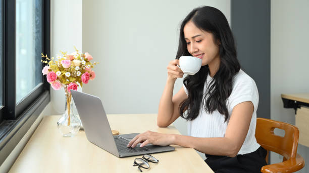 istock Pretty young female freelancer drinking hot coffee and checking email on her laptop computer. 1401677177