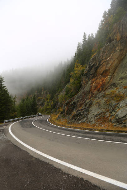 route brumeuse d’automne montée - asphalt two lane highway natural phenomenon fog photos et images de collection