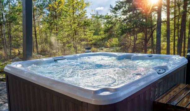 A warm hot tub in a beautiful forest landscape at sunset. You can relax outdoors in nature while enjoying the warmth of the hot tub.