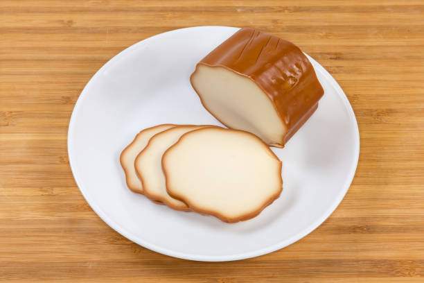 istock Partly sliced smoked processed cheese on dish on wooden surface 1401689094