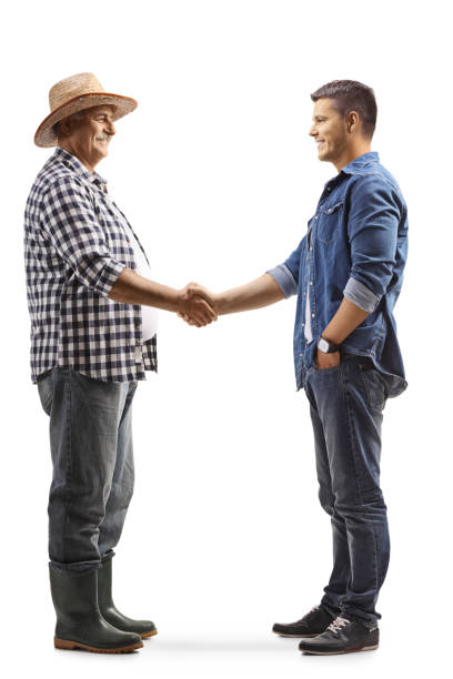 full length profile shot of a mature farmer shaking hands with a young casual man - agriculture teamwork farmer people imagens e fotografias de stock