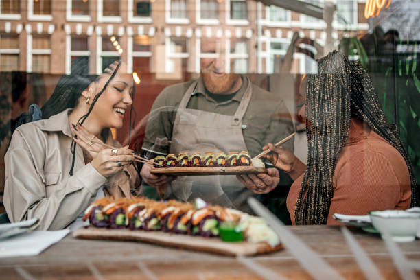 地元のレストランでビーガン寿司を共有することを楽しんでいる友人 - buffet japanese cuisine lifestyles ready to eat ストックフォトと画像