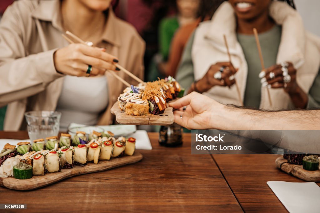 Friends enjoying sharing Vegan Sushi in a local restaurant Sushi Stock Photo