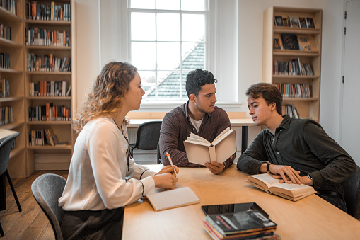 Three university students working together in a public library