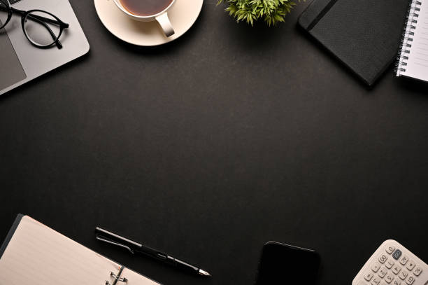 istock Workspace background with copy space surrounded by office accessories on black background. 1401695918