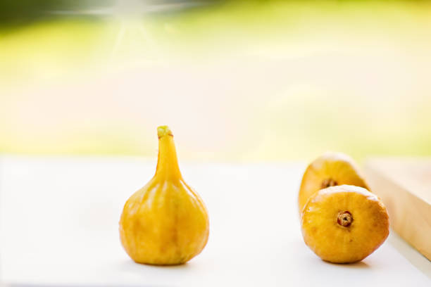 Three figs and grapes and blurred beautiful background with yellow bokeh. Fruits. Shallow depth of field. Food.The artistic intend and the filters. Film style old lens. Airy atmosphere.