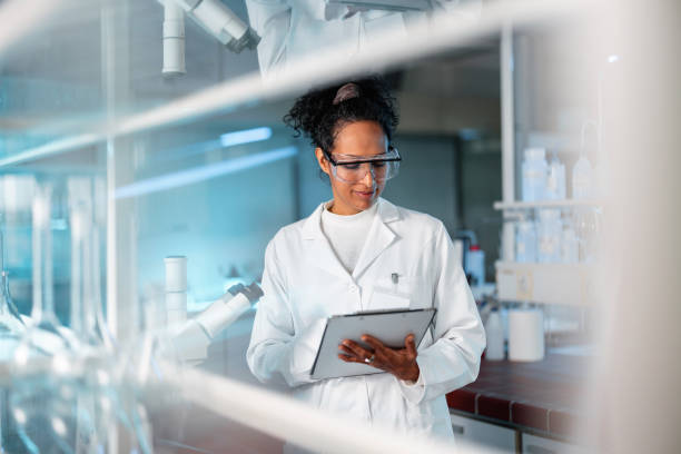 Young Female Scientist Noting Results Of Experiment In A Lab stock photo