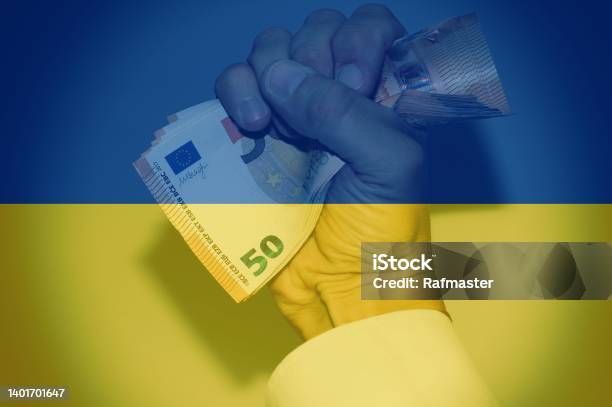 Hand Holding European Banknotes With The Ukrainian Flag As Background Concept Of Financial Help From Europe Stock Photo - Download Image Now