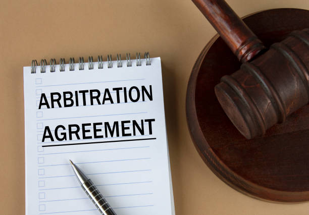 istock ARBITRATION AGREEMENT - words in white notebook on the background of the judge's hammer with stand 1401702454