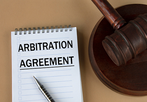 ARBITRATION AGREEMENT - words in white notebook on the background of the judge's hammer with stand