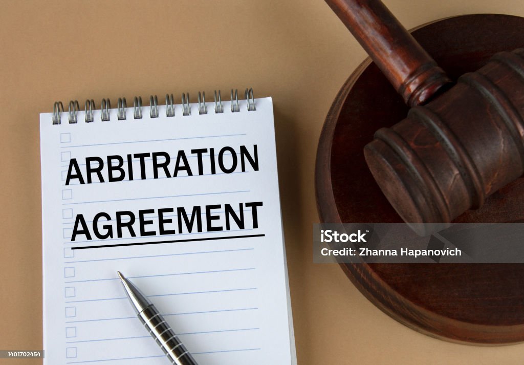 ARBITRATION AGREEMENT - words in white notebook on the background of the judge's hammer with stand Mediation Stock Photo