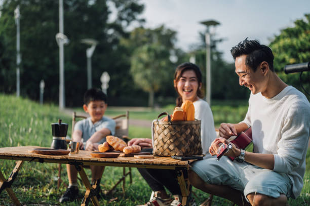 happy family enjoying in guitar music during their camping day - picnic summer break relaxation imagens e fotografias de stock