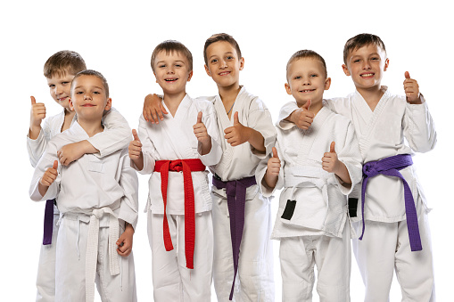 Sport, hobby, achievements. Group of happy children, beginner karate fighters in white doboks standing together isolated on white background. Concept of sport, education, skills, martial arts, ad.