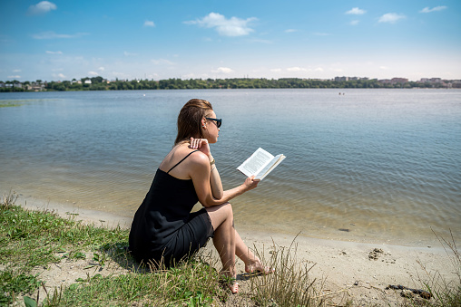 prety young woman in summer day read book near a lake, lifestyle